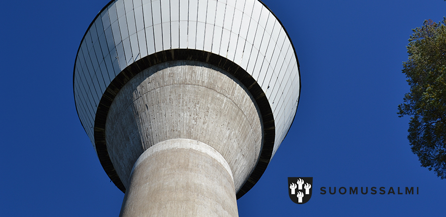 Vesitornin yläosa näkyy kirkkaansinistä taivasta vasten. Oikealla männyn latvaa. 